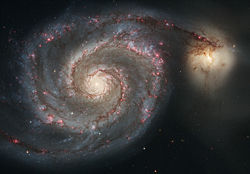 Strings of red H II regions delineate the arms of the Whirlpool Galaxy.