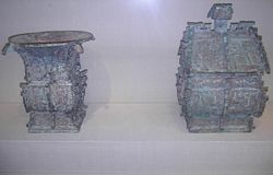Left: Bronze 方樽 fāngzūn ritual wine container dated about 1000 BCE. The written inscription cast in bronze on the vessel commemorates a gift of cowrie shells (then used as currency in China) from someone of presumably elite status in 周 Zhōu Dynasty society. Right: Bronze 方彝 fāngy&iacute; ritual container dated about 1000 BCE. A written inscription of some 180 Chinese characters appears twice on the vessel. The written inscription comments on state rituals that accompanied court ceremony, recorded by an official scribe.